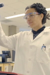 Woman scientist holds beaker up to light