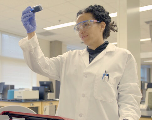 Woman scientist holds beaker up to light