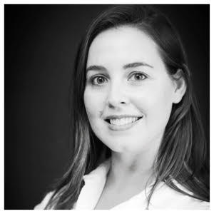 KatieWalsh_Headshot An image of film critic Katie Walsh. She wears her hair long and smiles in front of a neutral black background. She is wearing a white, collared shirt.