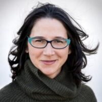 Headshot of Associate Professor of Transnational Italian Studies at UC Santa Barbara, Stephanie Malie Hom. The image depicts a woman with dark hair and blue rimmed glasses posing in front of a neutral background. She wears a turtleneck and is smiling.