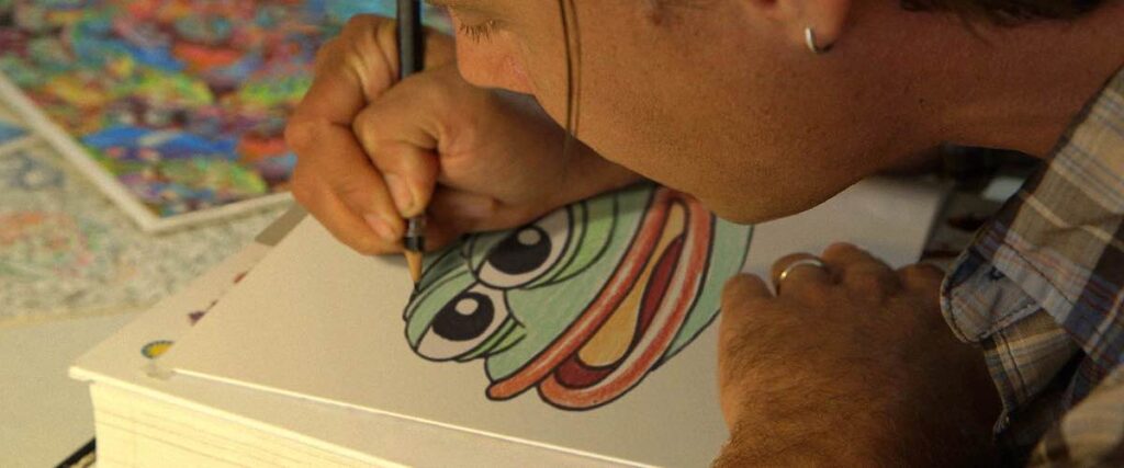 A still from the film Feels Good Man, depicting an artist at work drawing the smiling cartoon frog meme, Pepe.