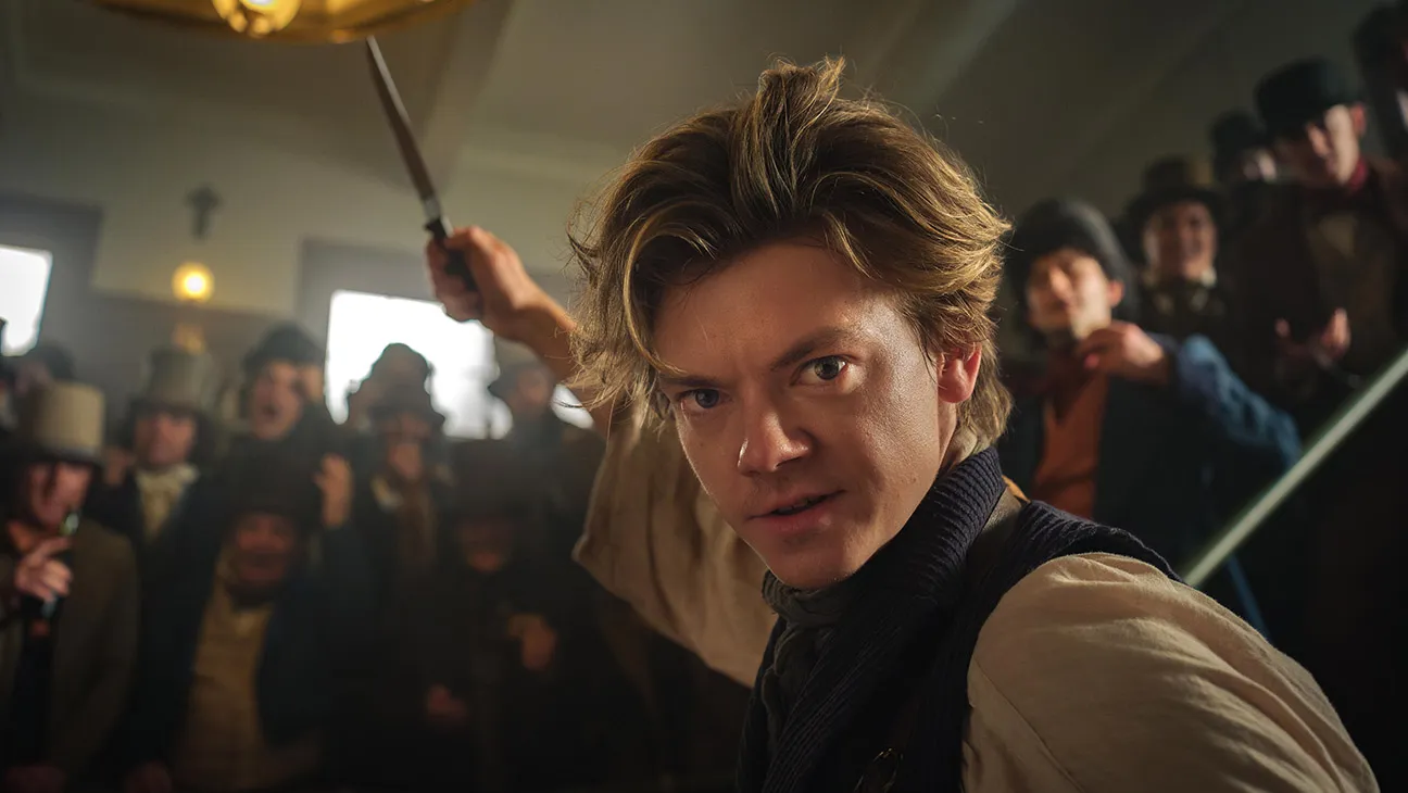 Actor Thomas Brodie Sangster appears in a still from The Artful Dodger television series. He is wearing 19th century period clothing and brandishing a scalpel.