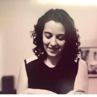 Shiva Balaghi, Ph.D., appears in black and white against a light background. She is wearing a sleeveless dark top and looking downward.